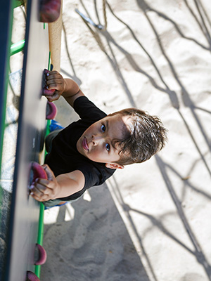 A boy climbing on a climbing wall attached to a UniPlay unit.